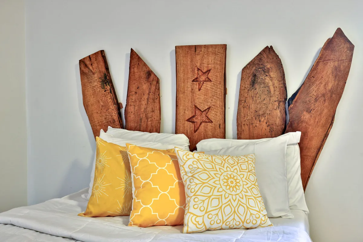 A cheerful bedroom featuring a wooden headboard, yellow pillows, and soft lighting. The space feels cozy and welcoming, designed for relaxation and comfort.