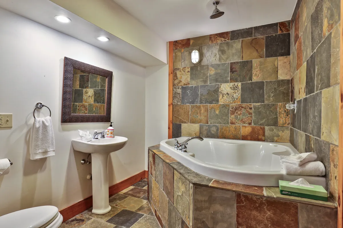 A tranquil bathroom showcasing a modern jetted tub, large mirror, and stylish sink, designed for relaxation and self-care after a long day.
