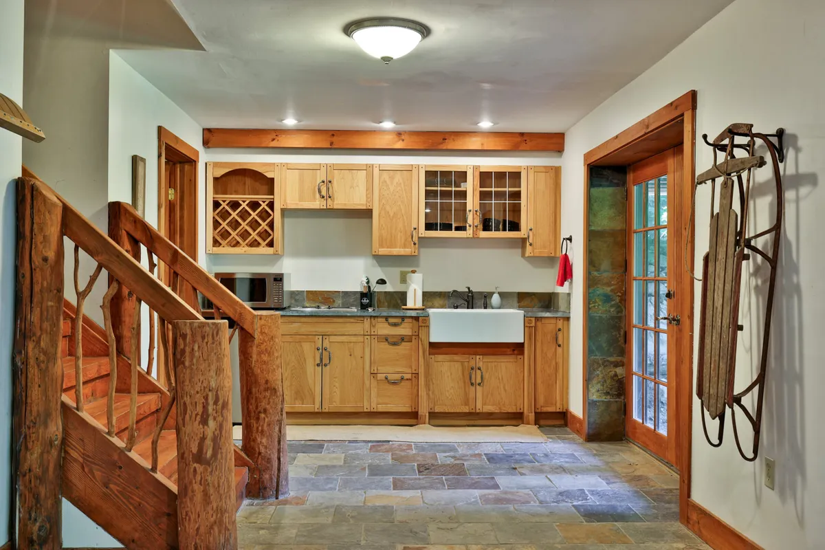 A cozy, inviting kitchen featuring high-end cabinetry, a spacious farmhouse sink, and French doors leading out to the surrounding landscape. The scene is set for cooking, entertaining, and sharing stories in a warm, communal space.